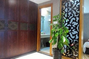 Una habitación con un armario de madera, una planta en maceta y un biombo decorativo.
