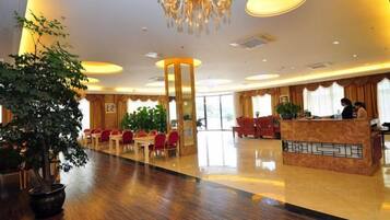 Un hall d’hôtel comprenant un comptoir d’accueil, un espace salon et une grande plante en pot.
