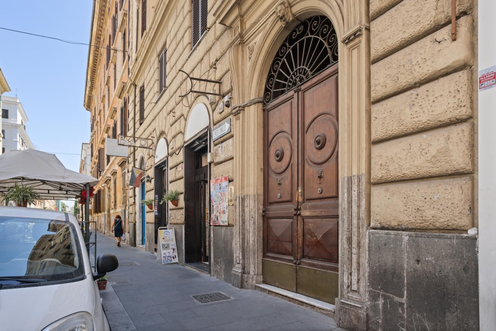 A street view with a building featuring a large wooden door and a sign above it.