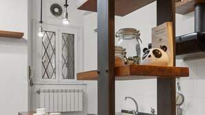 A modern kitchen with a wooden table, chairs, and a built-in shelf with kitchen items. - Pretorius Design Loft - Near Termini Station by RHR (ROMA)