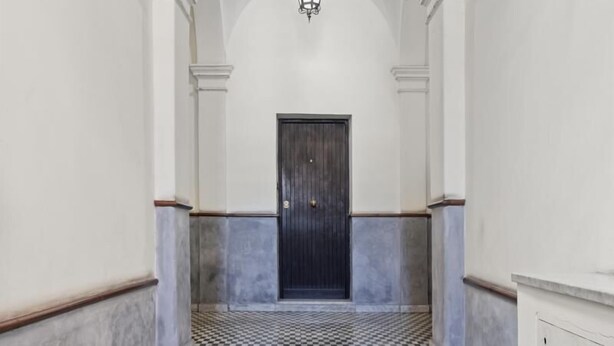 A hallway with a checkered floor, a dark door at the end, and a painted ceiling with architectural details. - Pretorius Design Loft - Near Termini Station by RHR (ROMA)