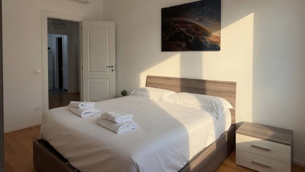 A bedroom with a bed, a nightstand, a wall-mounted air conditioner, a door, and a painting. - Modern Apartment near Tiburtina Station by RHR (ROMA)
