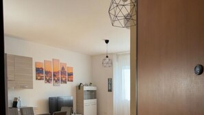 A modern living room with a dining area, wooden flooring, a blue sofa, and a geometric pendant light. - Modern Apartment near Tiburtina Station by RHR (ROMA)