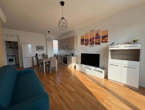 Un apartamento moderno con comedor, cocina, sala de estar y televisor.