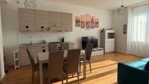 A modern kitchen with wooden cabinets, a dining area with chairs, a TV, and artwork on the wall. - Modern Apartment near Tiburtina Station by RHR (ROMA)