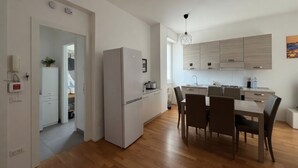 A modern kitchen with a dining area, wooden flooring, and a geometric light fixture. - Modern Apartment near Tiburtina Station by RHR (ROMA)