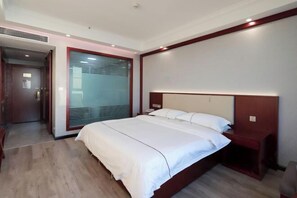 Una habitación de hotel moderna con una cama grande, un cabecero de madera y una mesita de noche pequeña.
