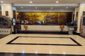 A reception area with a reception desk, seating, and a large decorative wall. - Huoqiudu International Hotel (Huoqiu)