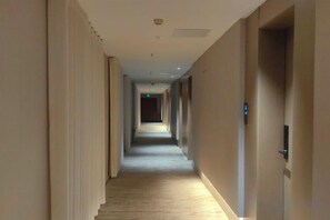 A long, narrow hallway with doors on both sides, leading to rooms. - Huoqiudu International Hotel (Huoqiu)