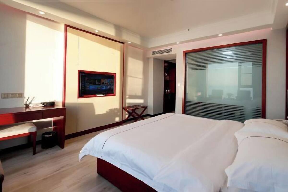 Una habitación de hotel moderna con una cama grande, un escritorio y un televisor.