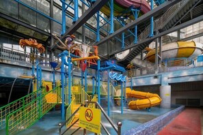 Ein mehrstöckiger Indoor-Wasserpark mit Rutschen, einem Pool und einem Warnschild.
