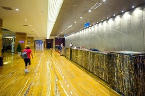 Un hall d’accueil d’hôtel avec un sol en marbre, un comptoir d’accueil et un aménagement intérieur moderne.