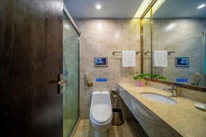 Une salle de bain moderne équipée de toilettes, d’un lavabo, d’un miroir et d’une poubelle.