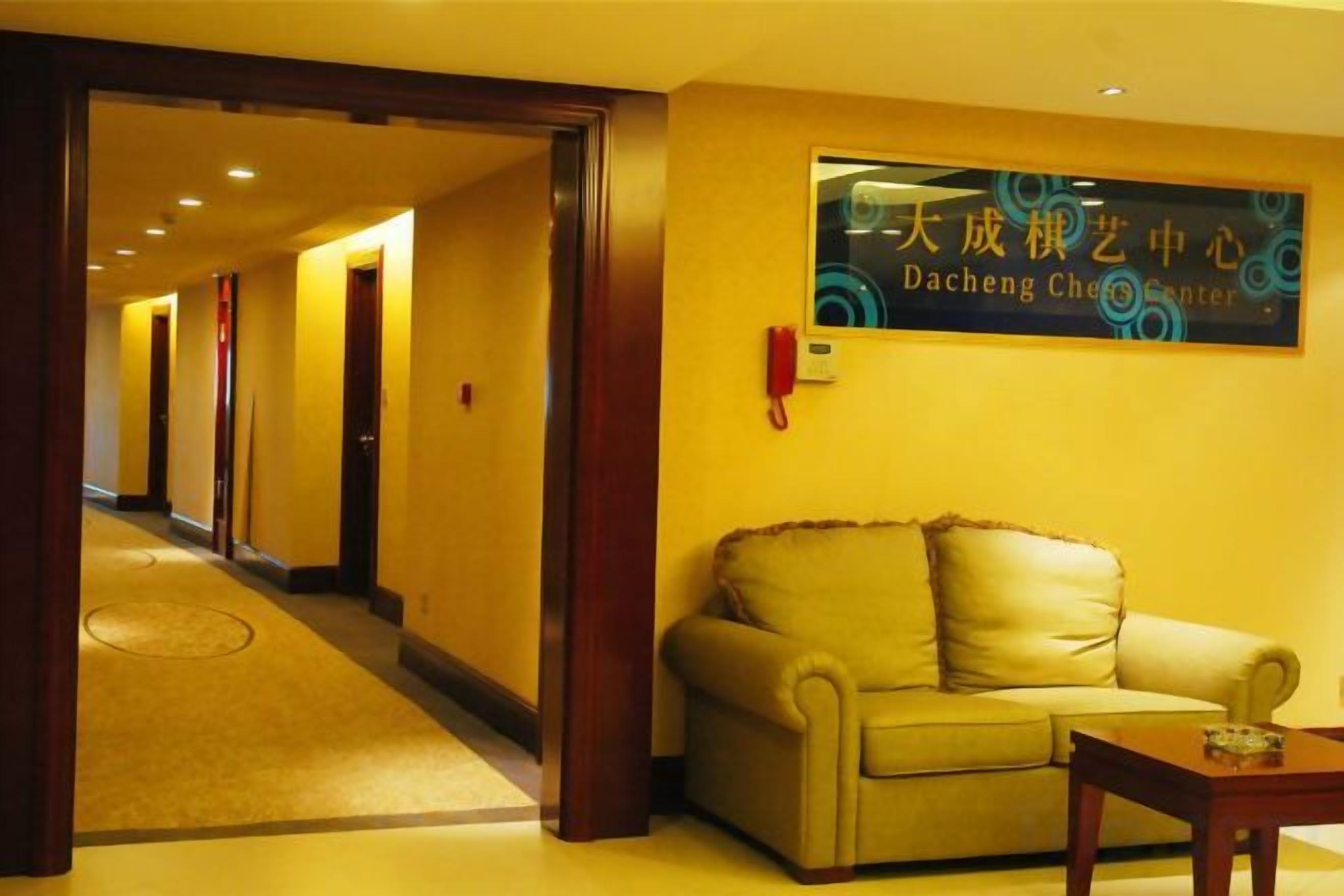 Un vestíbulo de hotel con una recepción, un sofá y un cartel en idioma extranjero.