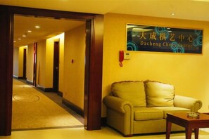 Un hall d’hôtel avec un comptoir d’accueil, un canapé et un panneau en langue étrangère.