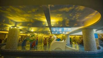 An indoor water feature with a swan sculpture, a colorful fish sculpture, and a ceiling with a cloud pattern.