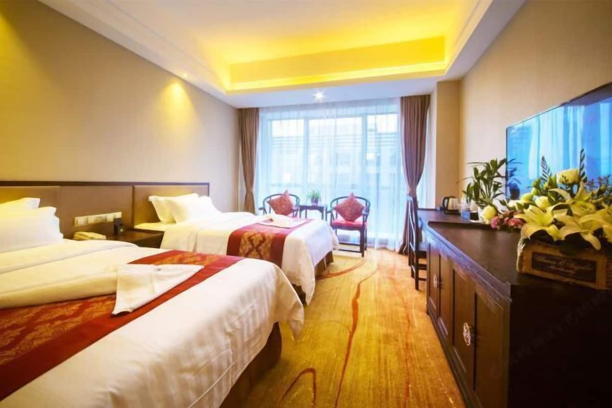Ein Hotelzimmer mit zwei Betten, einem Schreibtisch, einem Stuhl und einem Fernseher.
