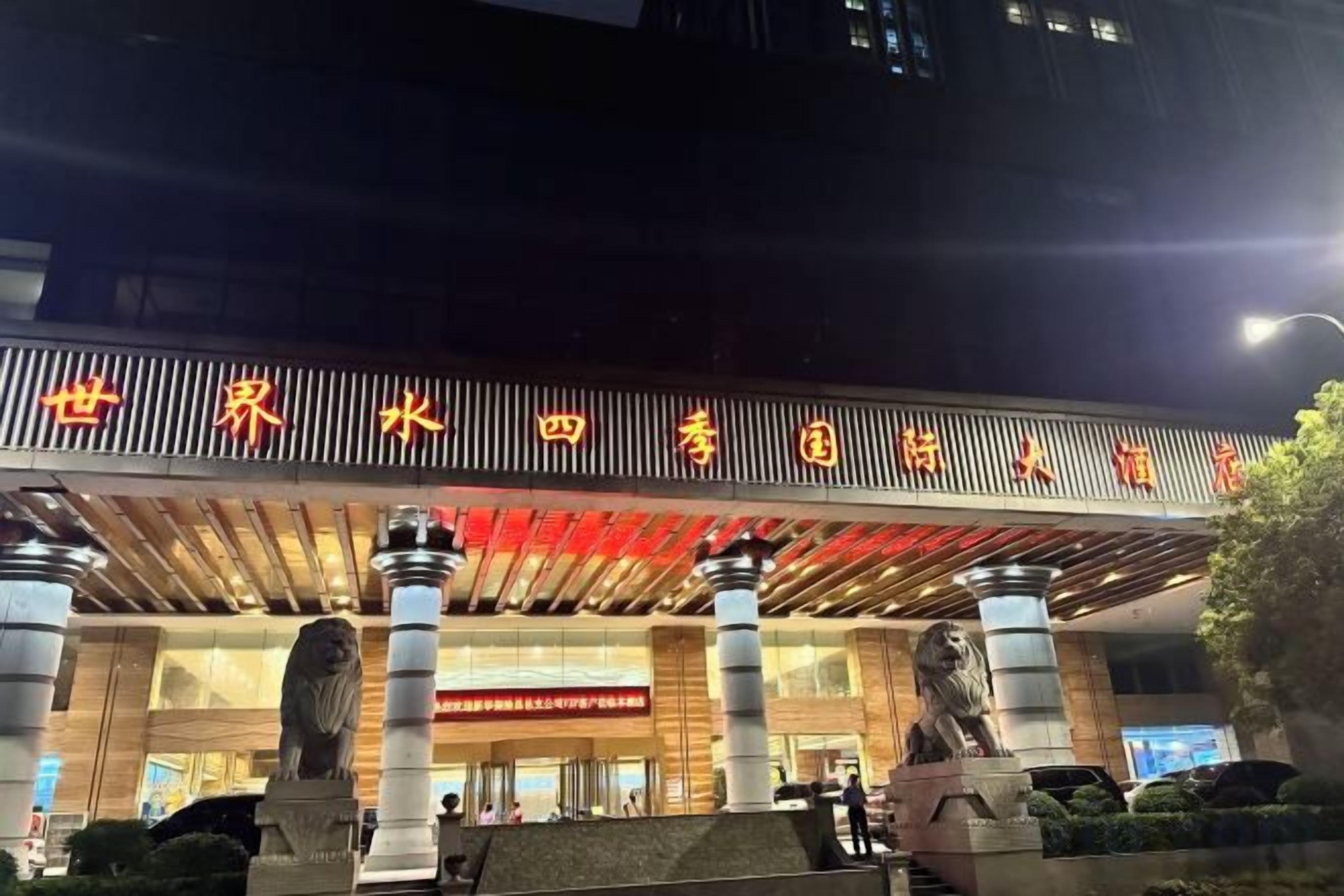 Entrada de hotel con un letrero iluminado, columnas y estatuas.