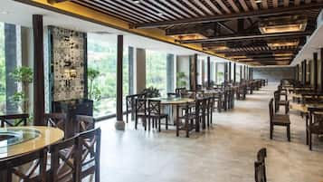 Amplo espaço interno com várias mesas e cadeiras, janelas grandes e design de teto moderno.