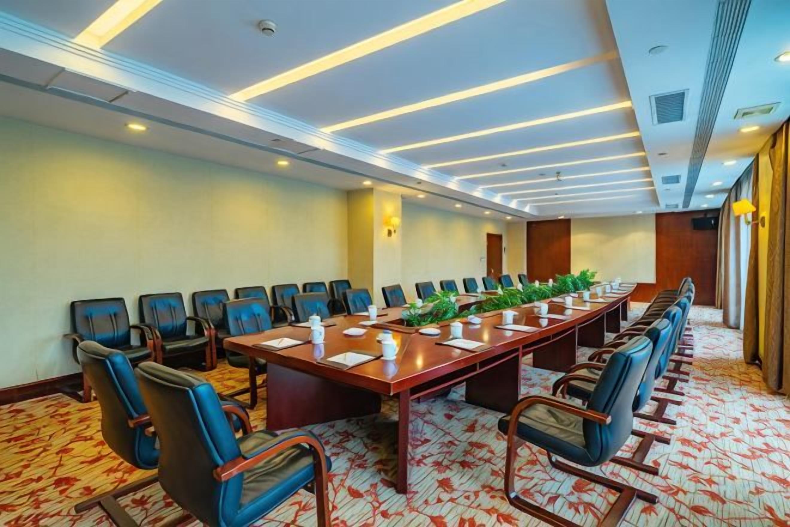 A conference room with a long table, chairs, and a carpeted floor.