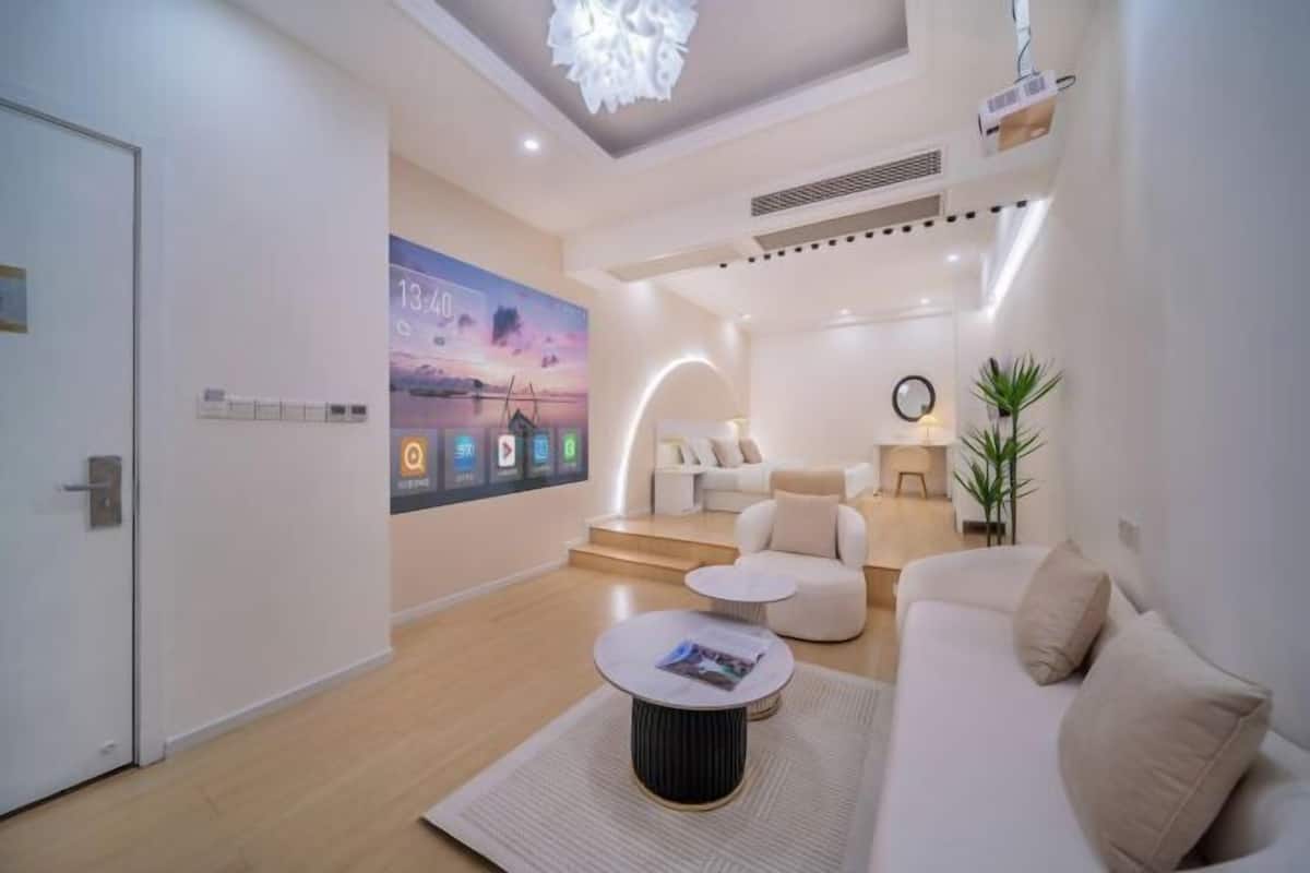 A modern living room with a sofa, coffee table, and a TV displaying a sunset scene.