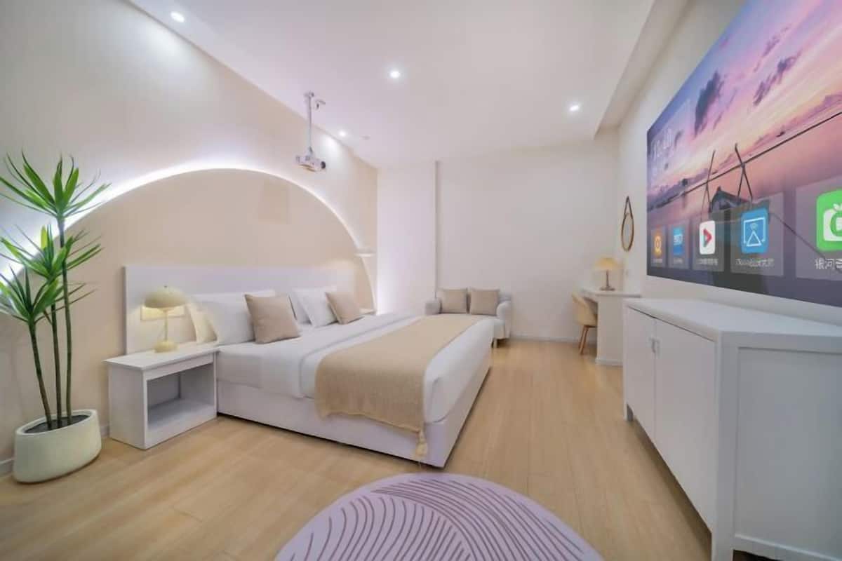 A modern bedroom with a bed, bedside table, lamp, and a TV displaying app icons.