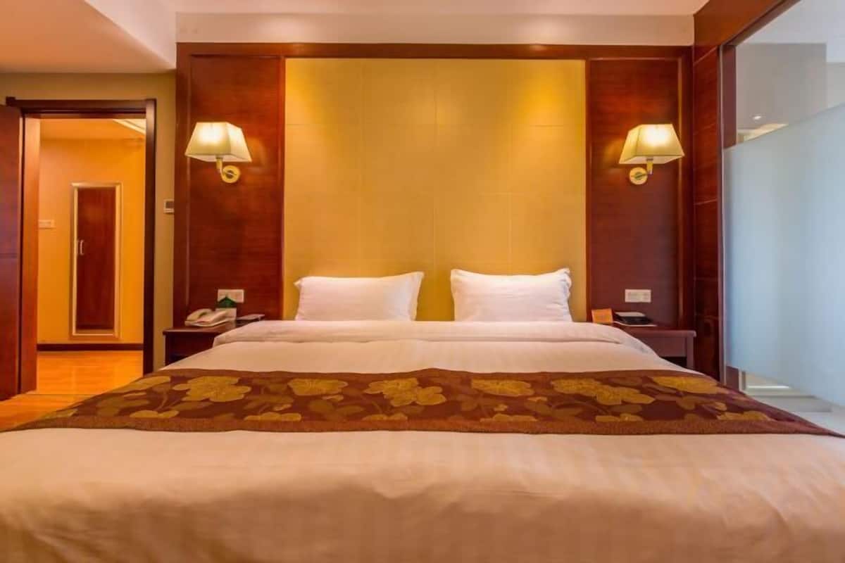 A hotel room with a large bed, two bedside tables, and two wall-mounted lamps.