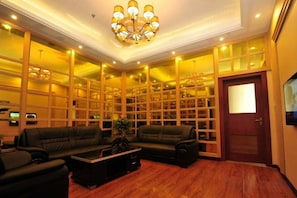 A spacious living room with a fireplace, comfortable seating, and a large bookshelf. - Tokang International Hotel (Tongshan)