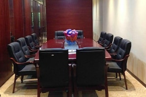 A conference room with a rectangular table surrounded by chairs, a floral centerpiece, and a red carpeted floor. - Tokang International Hotel (Tongshan)