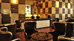 A modern restaurant with a checkered wall pattern, dark upholstered chairs, and a central bar area. - Tokang International Hotel (Tongshan)
