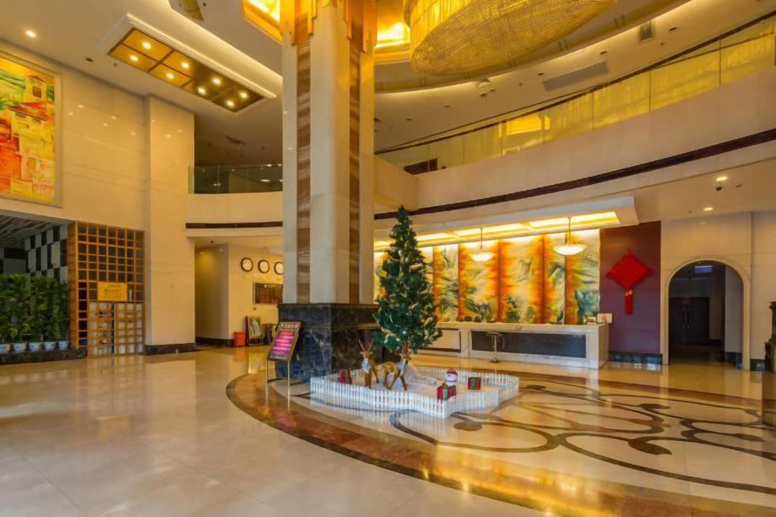 A spacious lobby with a reception desk, a Christmas tree, and a large pillar.