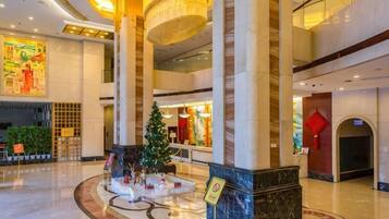 A spacious lobby with a Christmas tree, a reception desk, and a large chandelier.