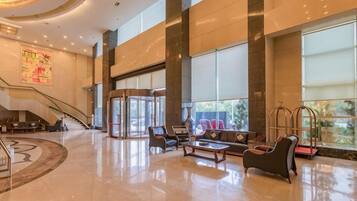 A spacious lobby with a central staircase, seating area, and large windows.