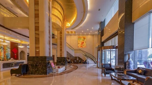 A spacious lobby with a reception desk, seating area, and a staircase leading to upper floors. - Tokang International Hotel (Tongshan)