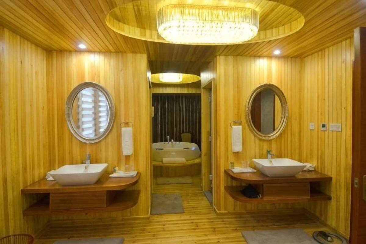 A wooden-paneled bathroom with two sinks, a large mirror, and a chandelier.