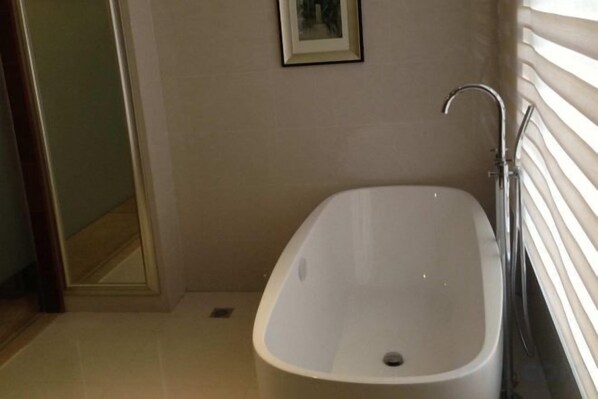 Un baño con una bañera independiente, zona de ducha y un cuadro en la pared.