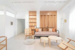 Une chambre à coucher moderne, avec un lit, deux chaises, une petite table et une étagère en bois intégrée.