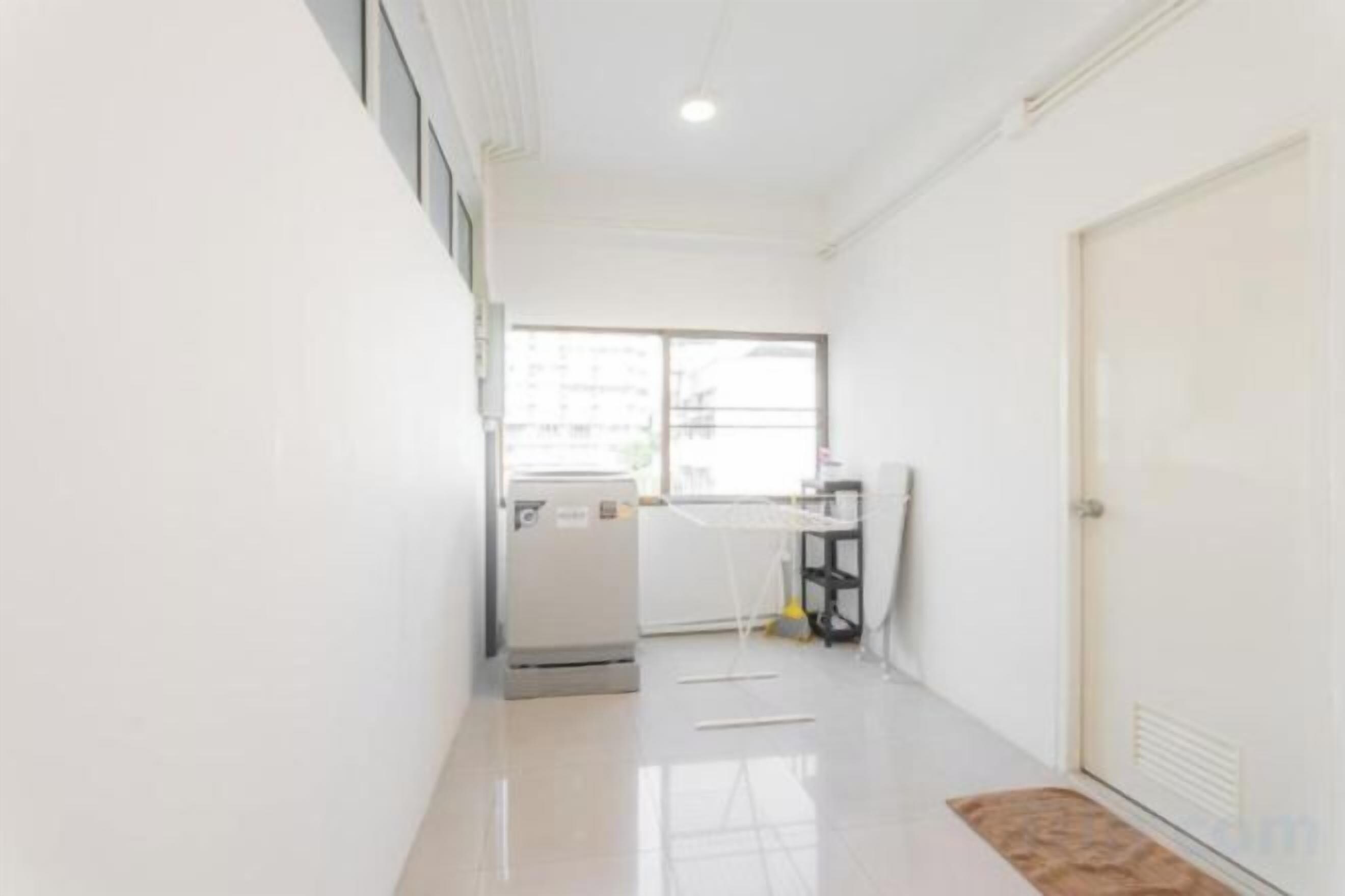 A hallway with a refrigerator, a window, and a door.