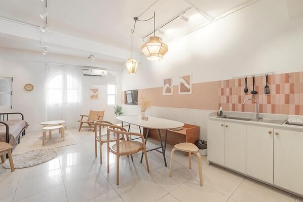 Uma cozinha moderna com armários brancos, uma mesa de jantar com cadeiras e iluminação pendente.