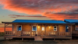 Une cabane en bois dotée d’un porche, de nombreuses fenêtres et d’un toit en métal.