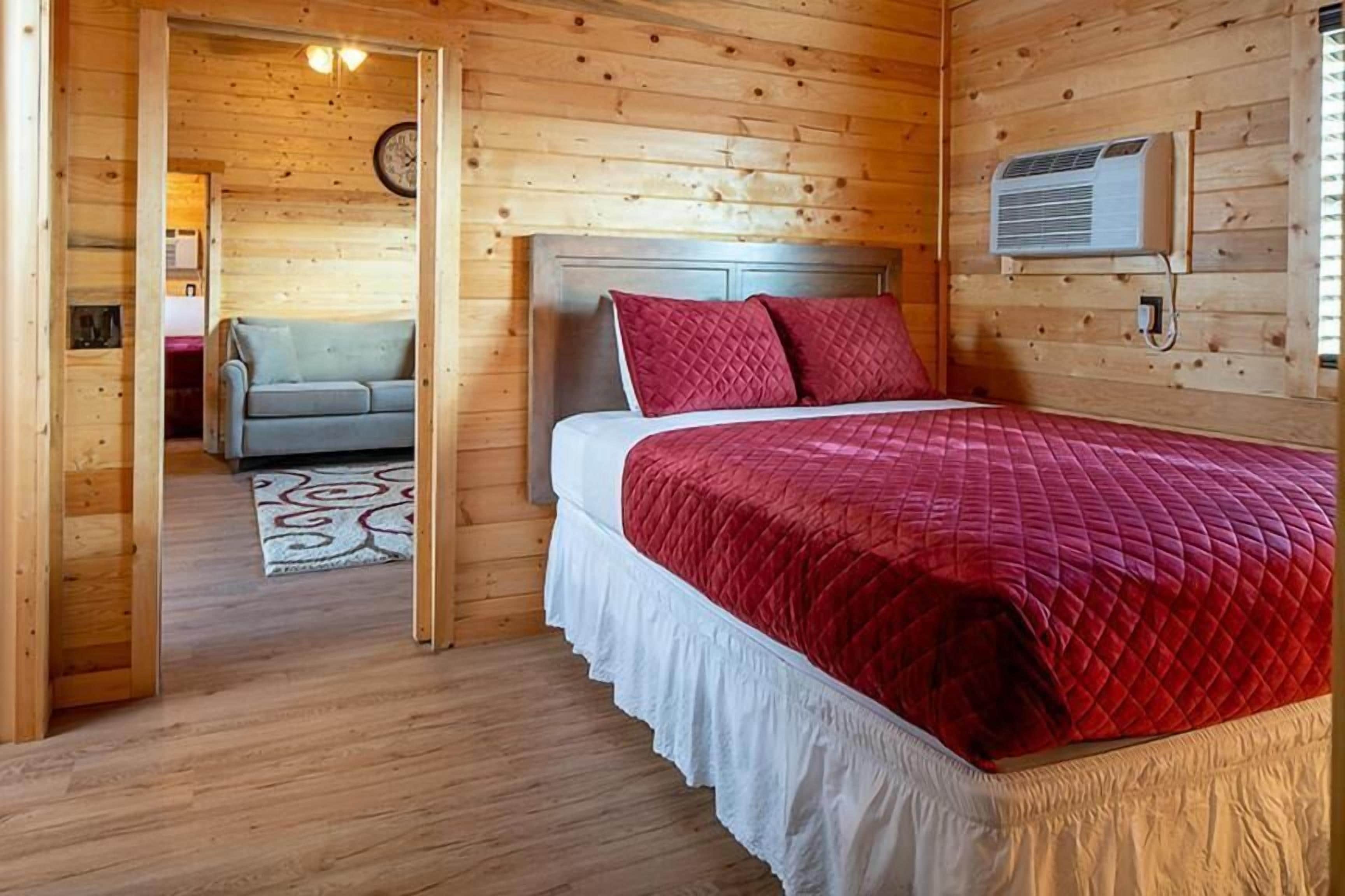 Une pièce en bois avec un lit, un canapé et un climatiseur fixé au mur.