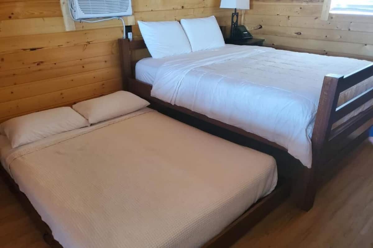 Uma cama de casal com cabeceira de madeira e mesa de cabeceira com abajur.