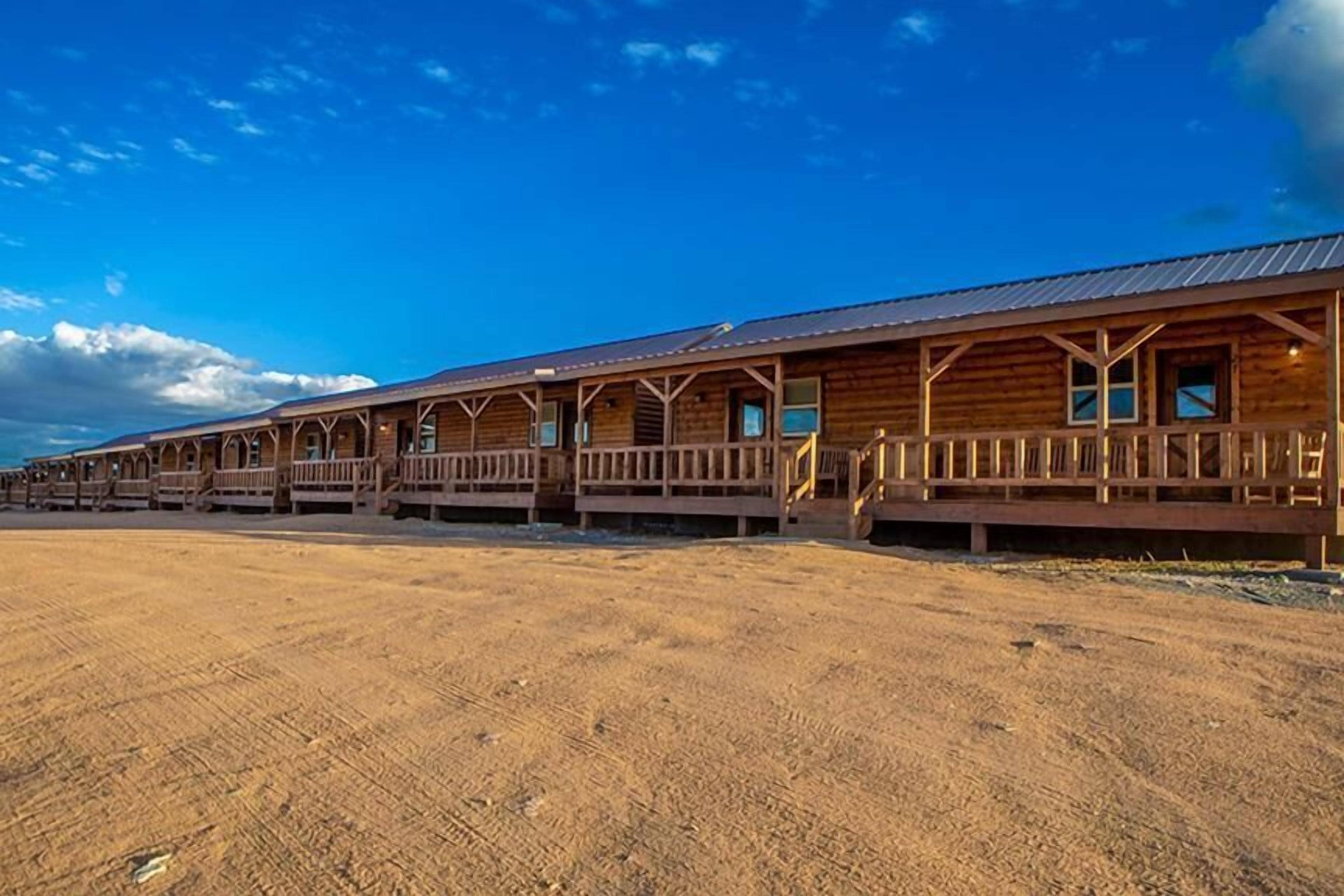 A row of wooden cabins with balconies, set against a clear blue sky.