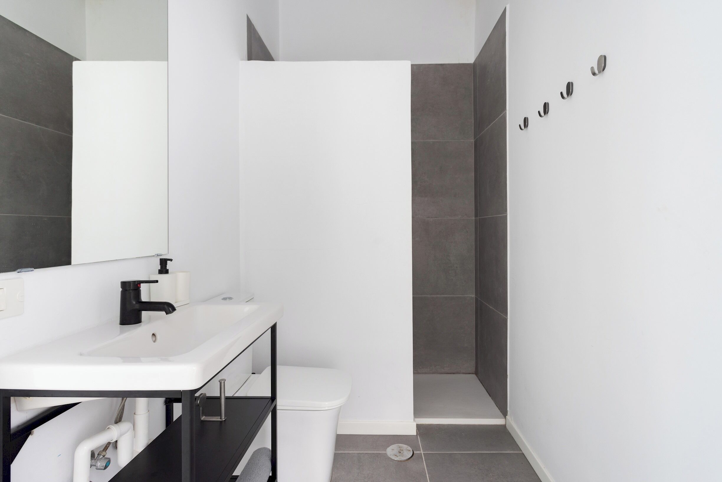 A modern bathroom with a white sink, black faucet, and a toilet.