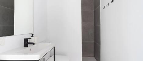 A modern bathroom with a white sink, black faucet, and a toilet.
