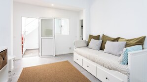 Ein moderner, gut beleuchteter Raum mit einem weißen Sofa, einem braunen Teppich und einem weißen Schrank.