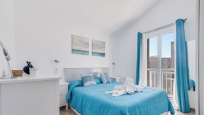 A modern bedroom with a large bed, a nightstand, a mirror, and artwork on the wall. - Home2Book Green Oasis Charming Duplex Maspalomas (Maspalomas)