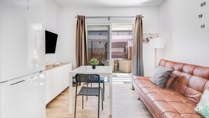 A modern kitchen with white cabinets, a dining table with two chairs, and a brown leather sofa. - Home2Book Green Oasis Charming Duplex Maspalomas (Maspalomas)