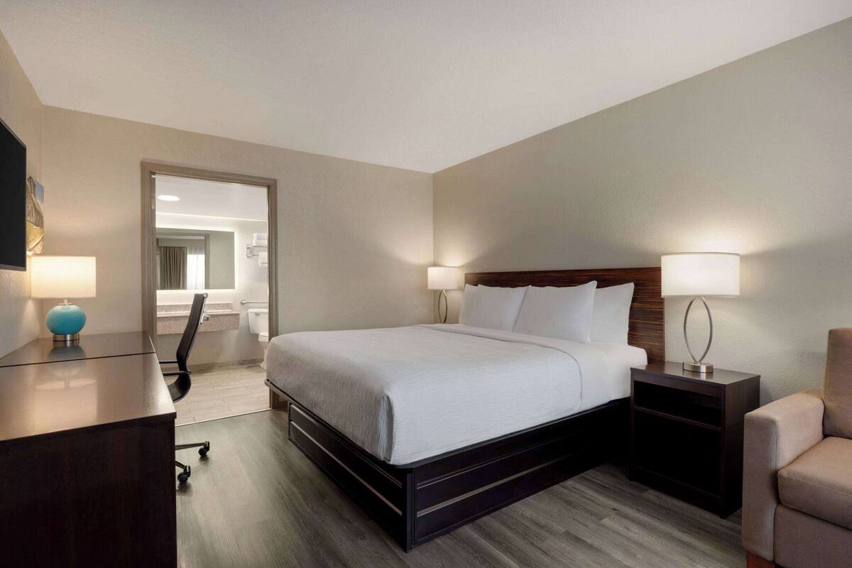 Une chambre d’hôtel avec un grand lit, des tables de chevet, un bureau et une chaise.