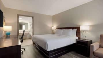 Una habitación de hotel con una cama grande, mesitas de noche, un escritorio y una silla.